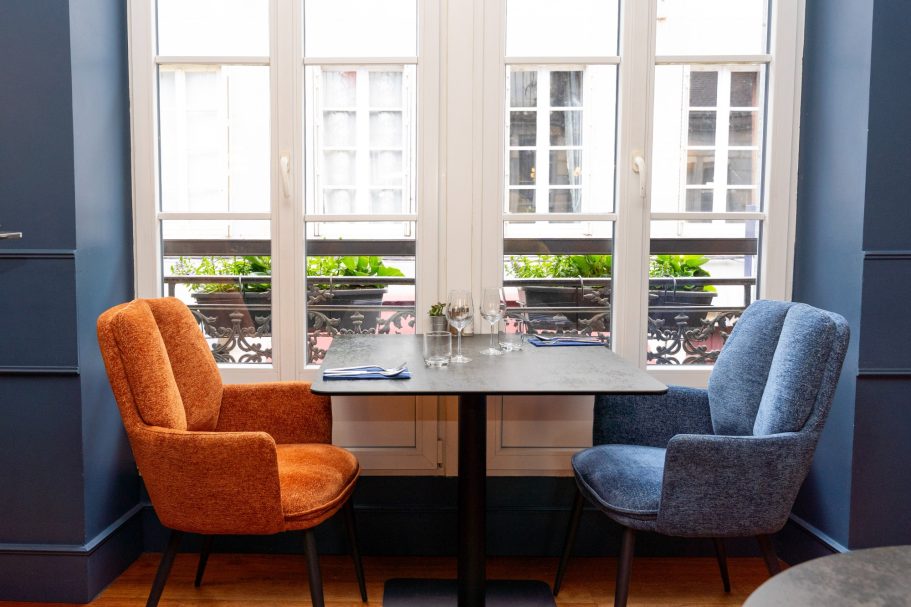 1er étage restaurant Besançon L'Y Gargotte Deux fauteuils, orange et bleu, autour d'une table près d'une fenêtre lumineuse.