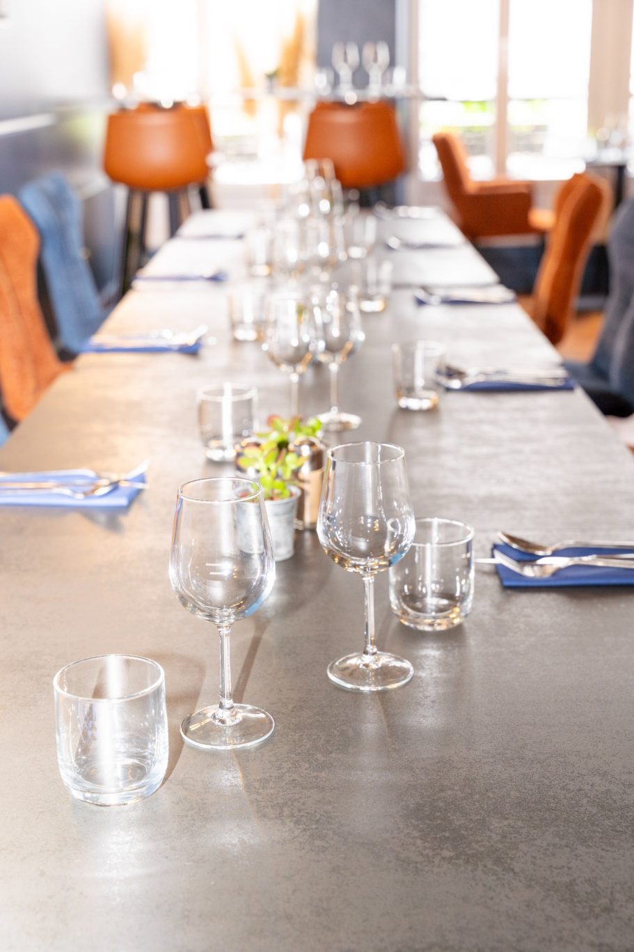 Table restaurant Besançon L'Y Gargotte Longue table dressée avec verres, couverts et centre de table fleuri.