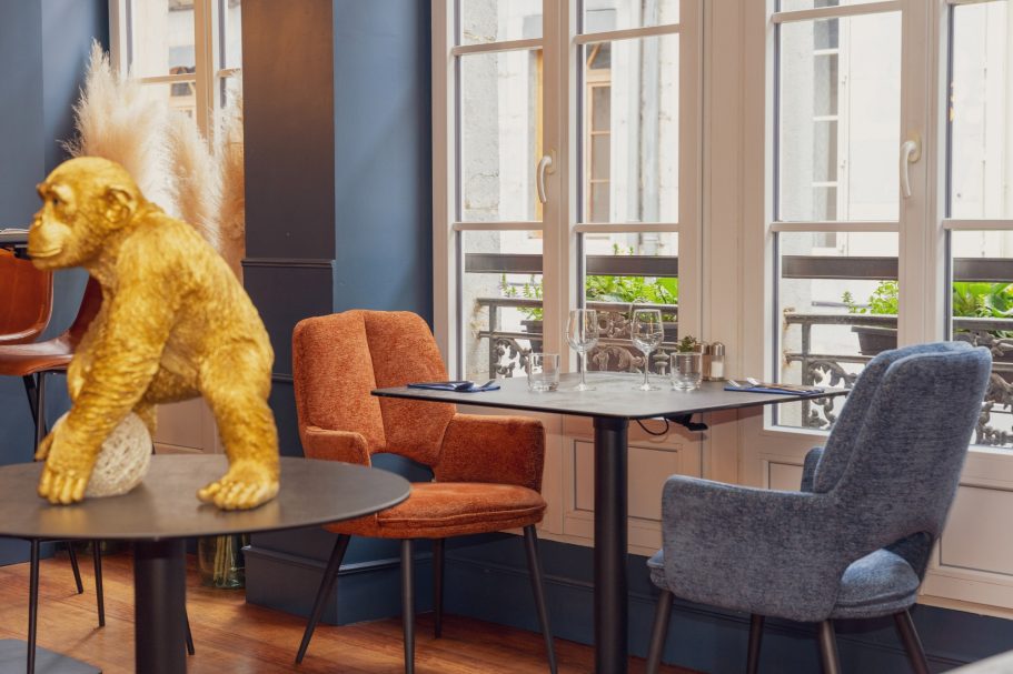 Décor 1er étage restaurant Besançon L'Y Gargotte Sculpture de gorille doré à côté de chaises colorées dans un café moderne.