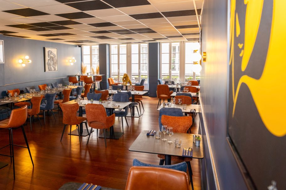 1er étage du restaurant Besançon L'Y Gargotte Intérieur d'un restaurant moderne avec des tables, chaises orange et murs bleus.