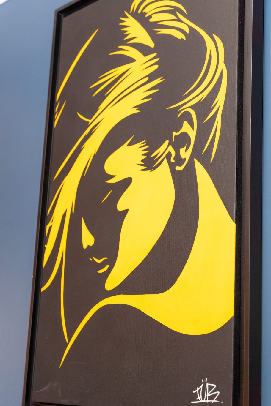 Décoration restaurant Besançon L'Y Gargotte Silhouette d'une femme aux cheveux blonds, sur fond noir et jaune.