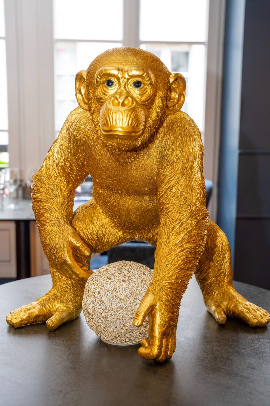 Décor d'exception restaurant Besançon L'Y Gargotte Sculpture d'un singe doré tenant une sphère sur une table.