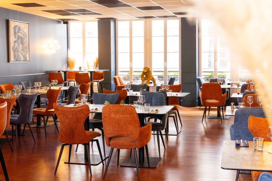 1er étage restaurant Besançon L'Y Gargotte Salle à manger moderne avec des chaises orange et bleues, grandes fenêtres et décoration élégante.